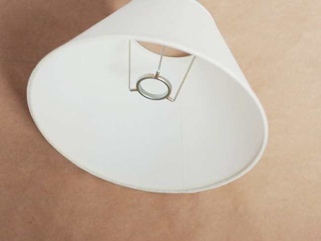 a plain white lampshade laying on the floor