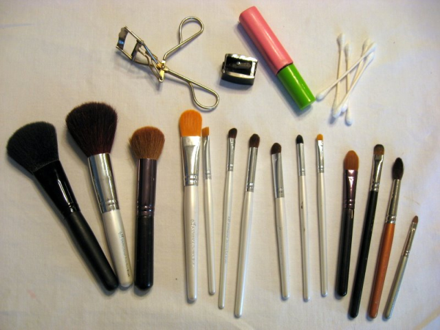 makeup brushes, a eyelash curler and mascara splayed on a table