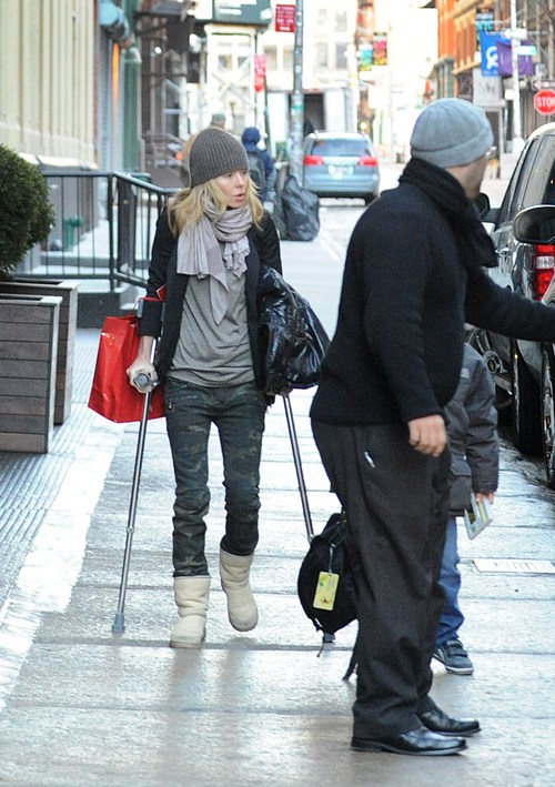 kelly ripa knit hat, crutches, boots, jeans, black jacket, scarf