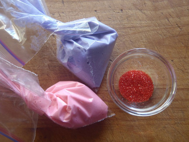 bags of purple and pink meringue to be piped with red sugar crystals