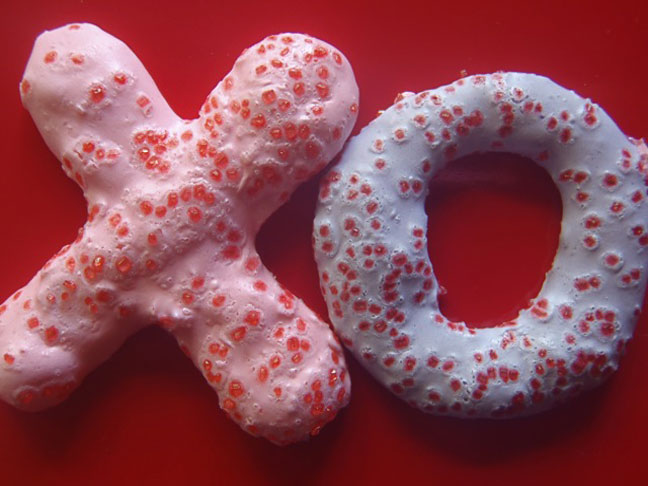 Meringue cookies shapes in to x and o's with red sugar on top 