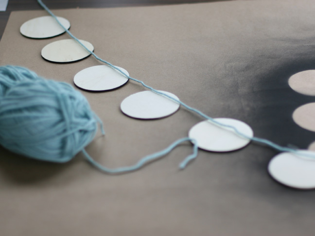 stringing blue yarn across white disks