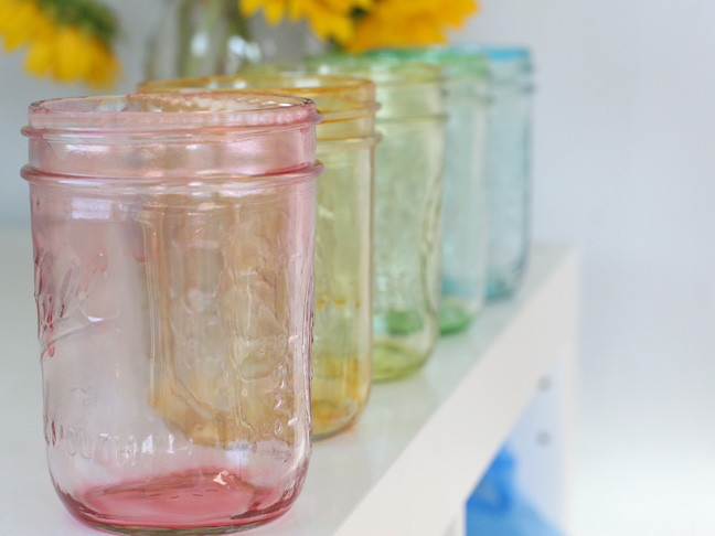 a rainbow of tinted mason jars on a white background