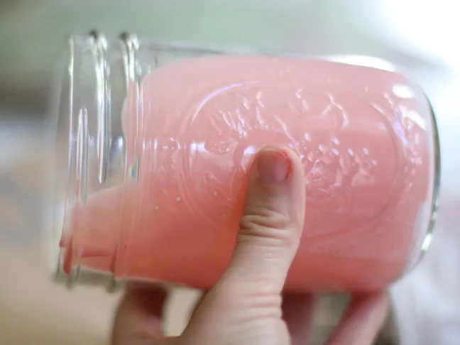 a empty mason jar with pink gooey material being moved around inside