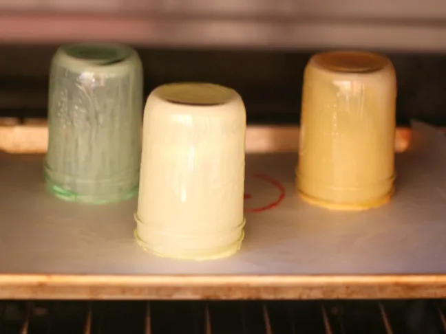 colored mason jars upside down drying on a cookie sheet in the oven