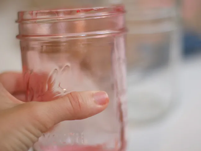 holding a pink tinged mason jar