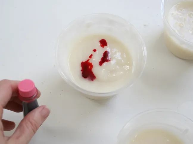 red food coloring is dropped in to the white slime mixture