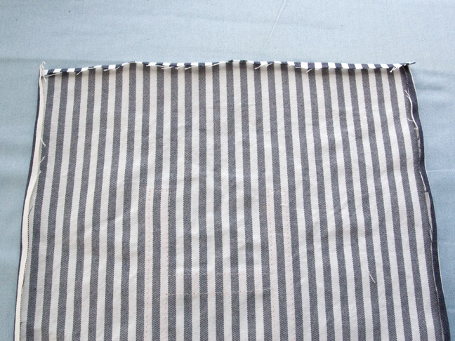 A piece of the blue and white pinstriped fabric is laying face down