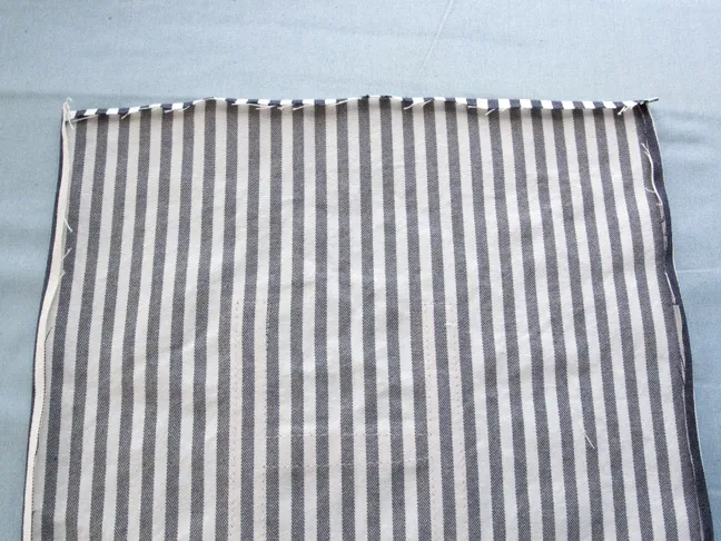 A piece of the blue and white pinstriped fabric is laying face down