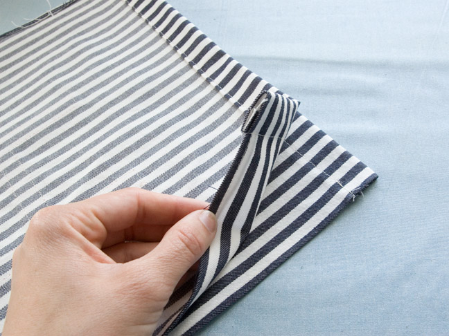 the fabric is folded over in half with one end being held up