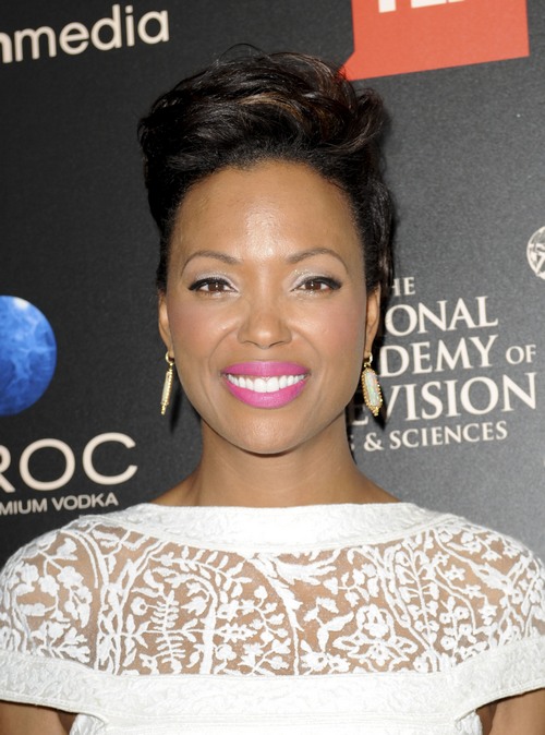 Aisha Tyler pictured smiling in a lace white dress