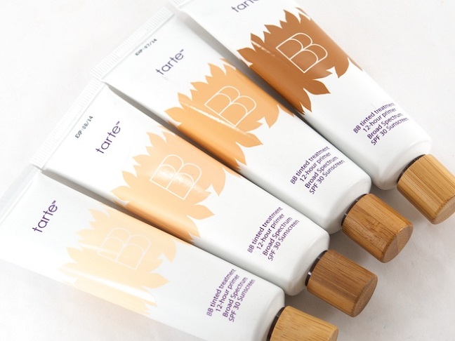 4 small white tubes of tarte bb cream with wooden covers laying side by side