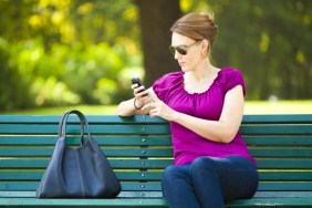 woman texting on park bench