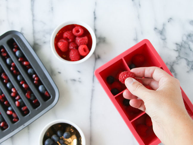 Add raspberries, blueberries, and pomegranate to ice cube trays