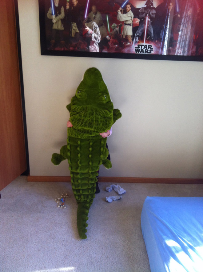 Little boy hiding behind alligator stuffed animal