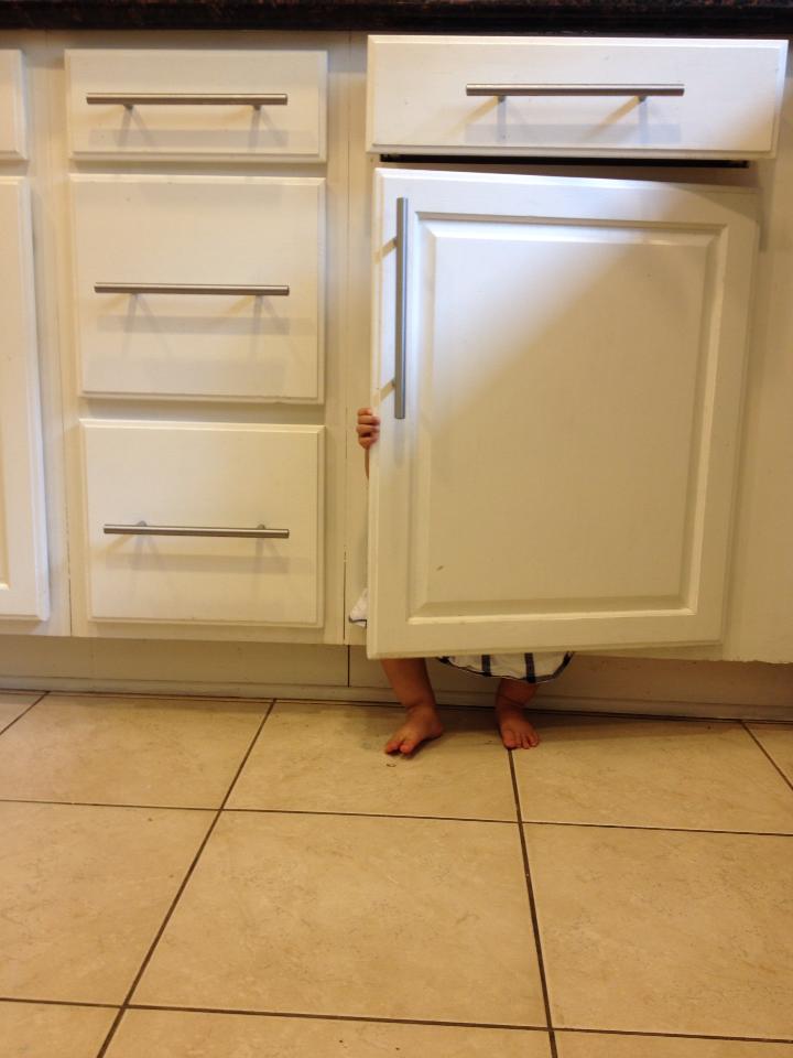 Little girl hiding behind a cabinet