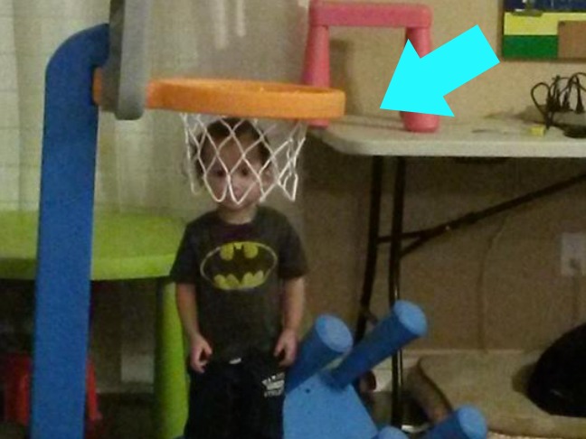 child trying to hide in a basketball hoop