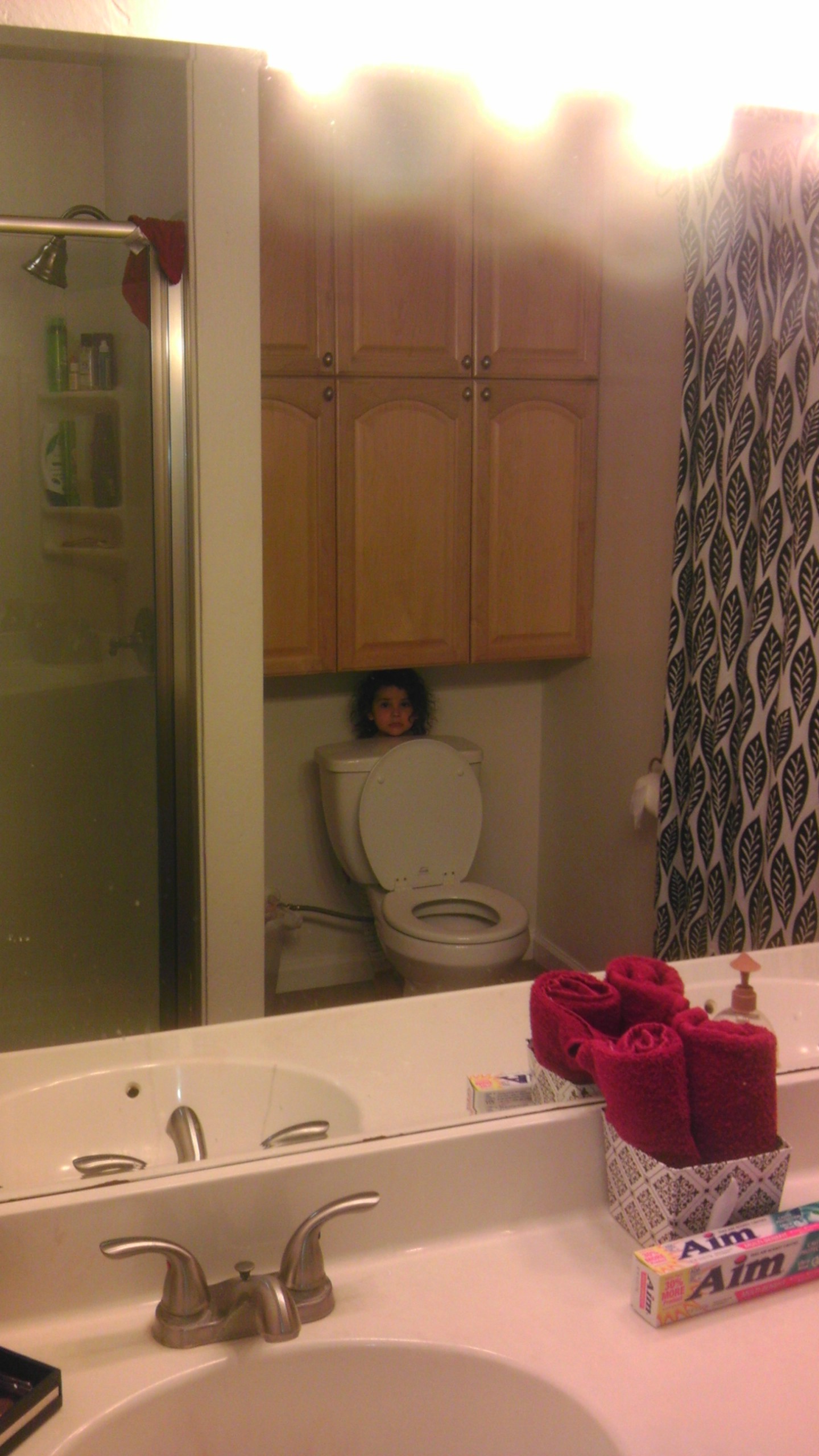 Little girl hiding behind a toilet