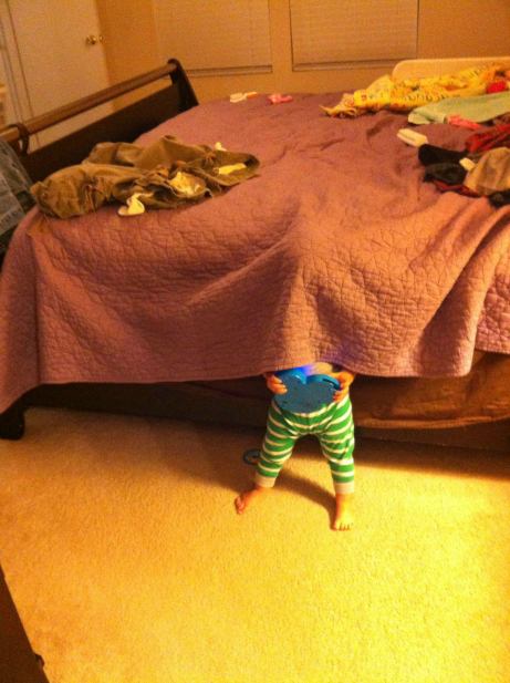 child hiding under a blanket holding toy
