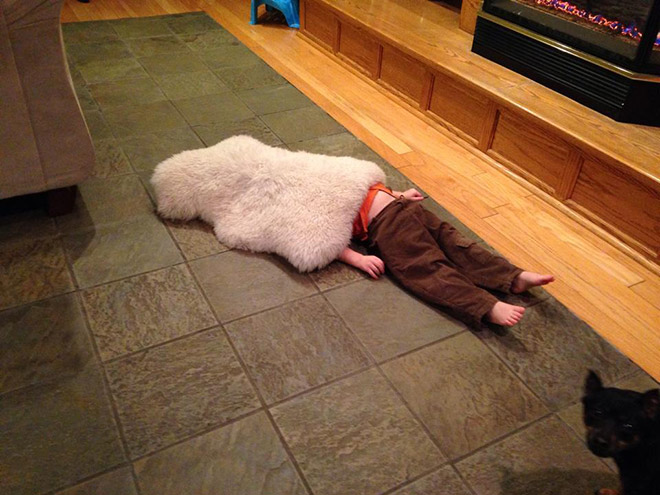 child laying on the floor with a cover