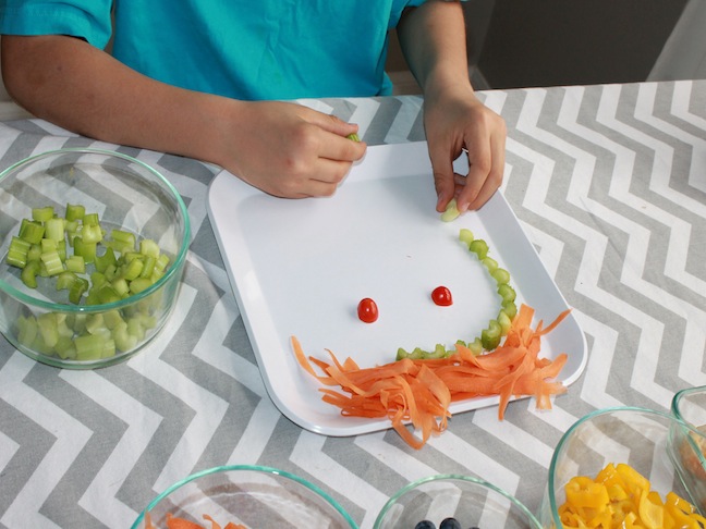 Child's Hands Making a Face out of Food on a Plate