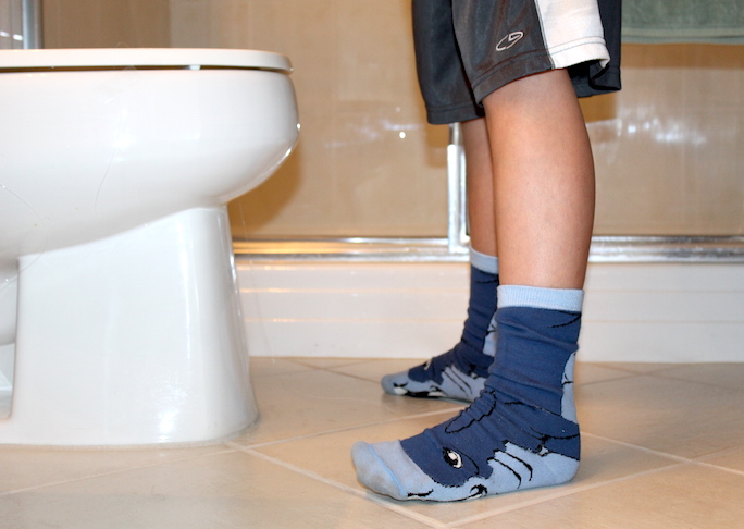 boy standing in front of toilet