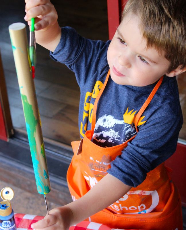 toddler-boy-painting-wood-dowel-diy-art-project-orange-apron