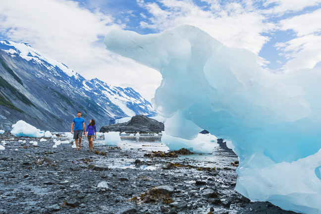 Young adult couple walk along the coastline littered with icebergs, Harriman Fjord, Prince William Sound, Southcentral Alaska