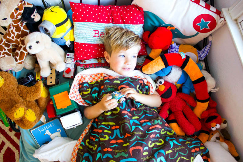 little boy in bed with all of his toys