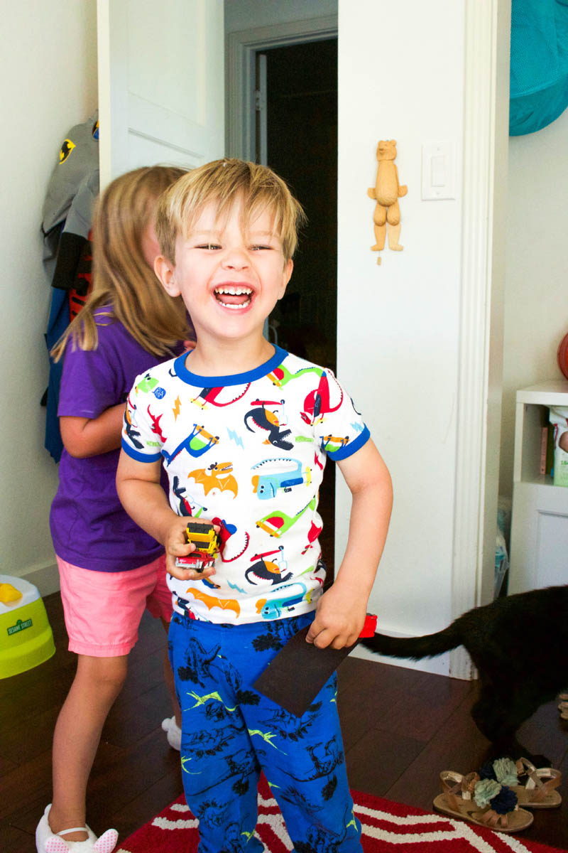 little boy laughing in his room with dinosaur pagamas