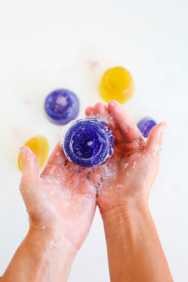 hands holding a purple disc of soap