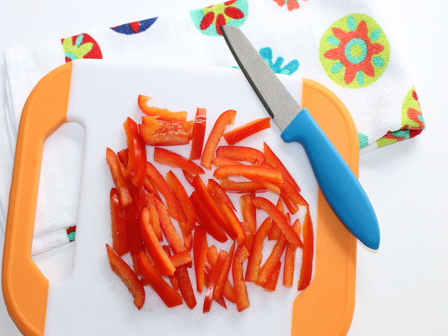 chopping red peppers on a cutting board