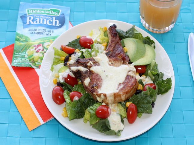 pork chop on top of green salad with tomatoes