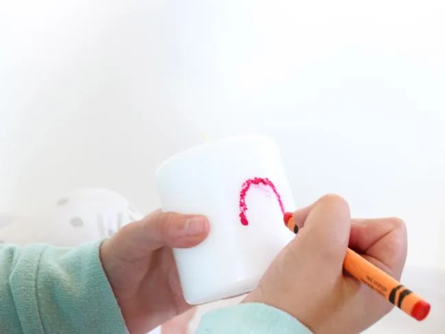 drawing heart with melted crayon on candle