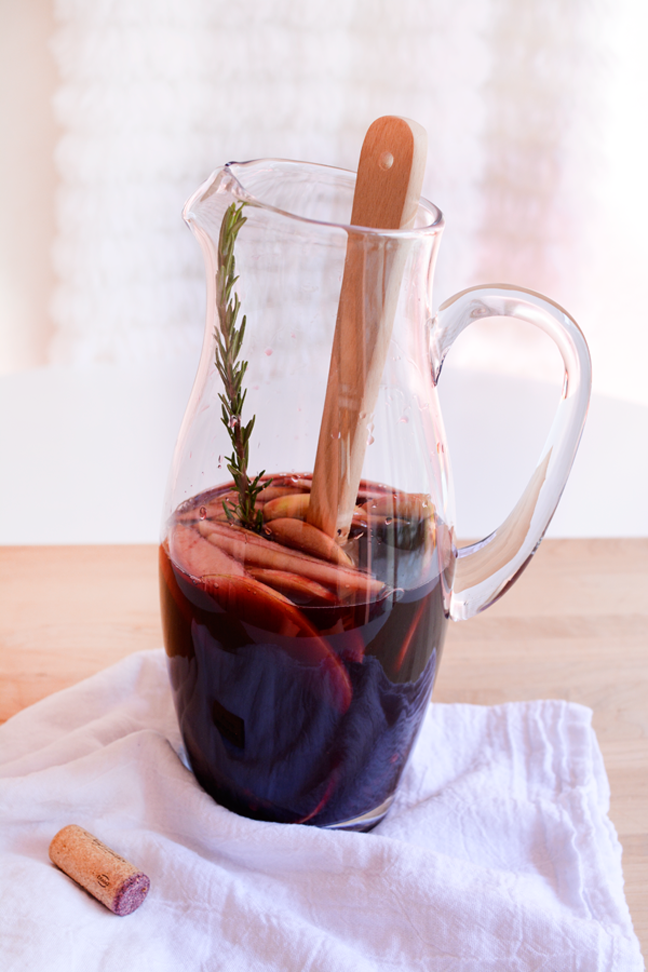 pitcher red wine sangria with rosemary sprig and wooden spoon