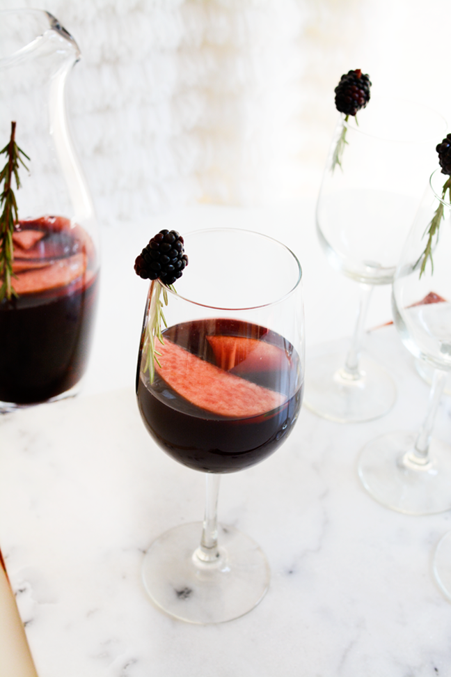 red sangria in white glass with blackberry garnish
