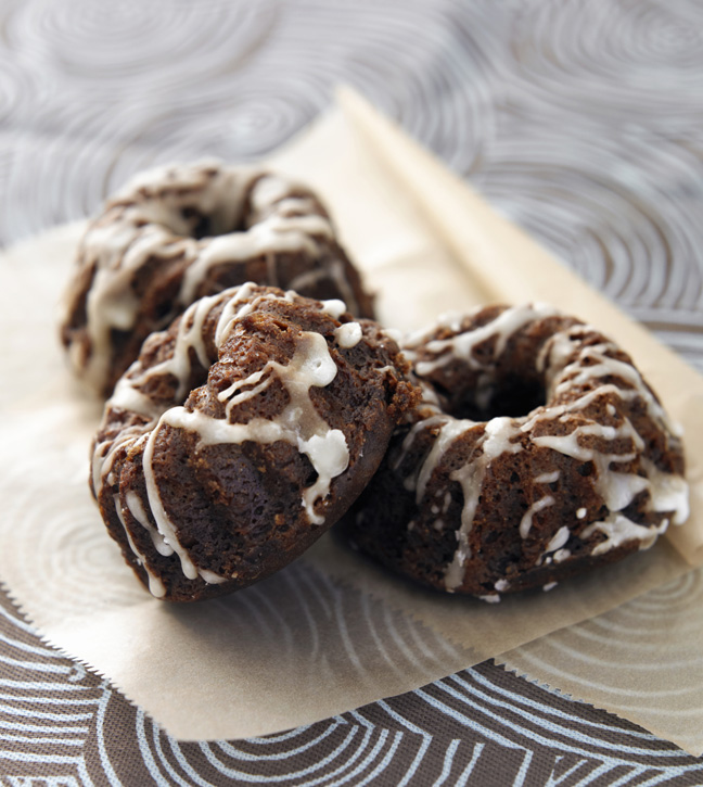 Three mini gingerbread bundt cakes with icing on paper, close-up