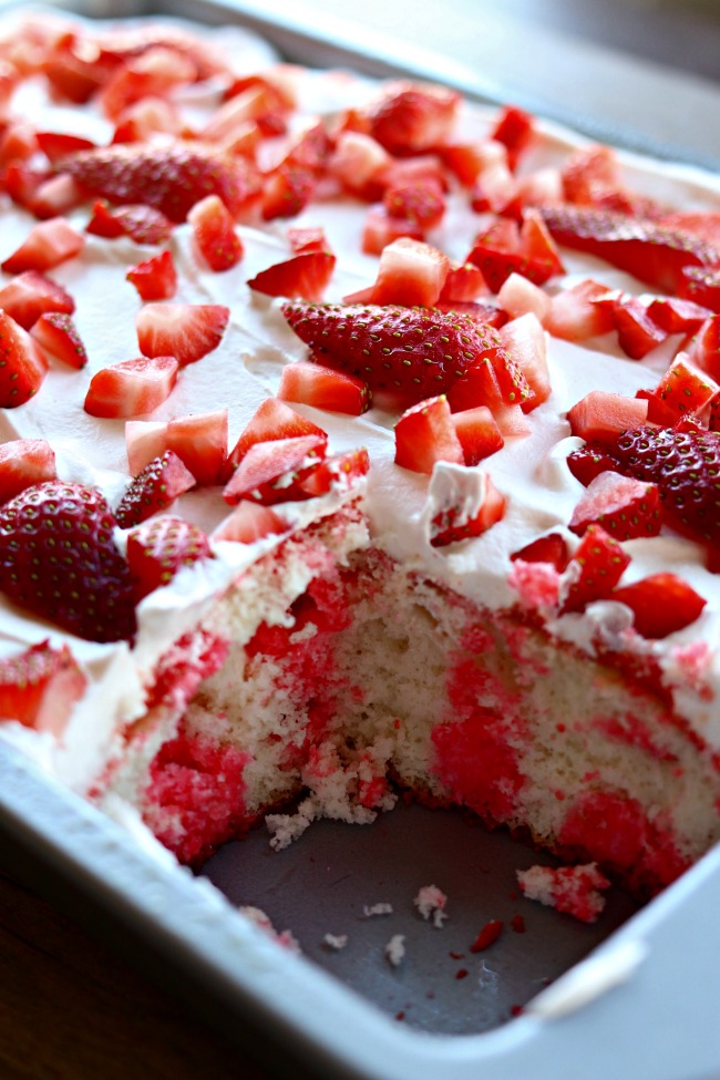 Strawberry Jello Poke Cake--an incredibly moist and easy-to-make poke cake that starts with a white cake mix. Strawberry gelatin is poured into the holes in the cake and then the cake is topped with whipped topping and fresh strawberries. Perfect for potlucks and gatherings!