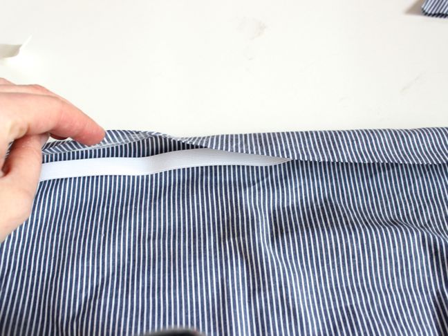 hand-folding-over-seam-on-a-blue-and-white-striped-shirt
