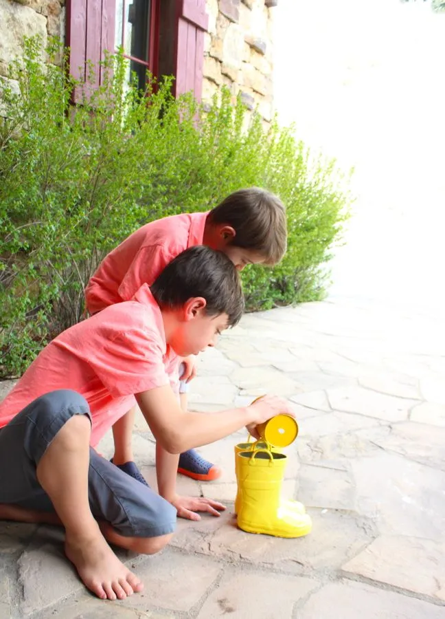 boys-filling-yellow-rain-boots-with-pebbles