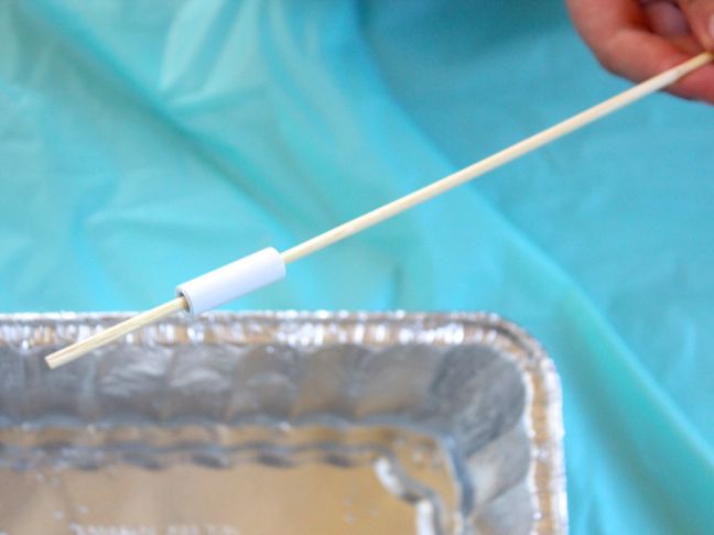 dipping a wood skewer with white bead into water