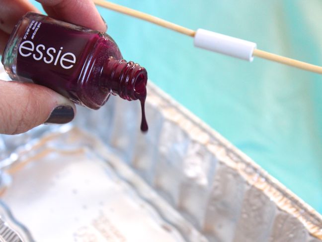 pouring burgundy nail polish into water