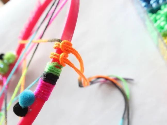 orange-yarn-knot-around-pink-embroidery-hoop