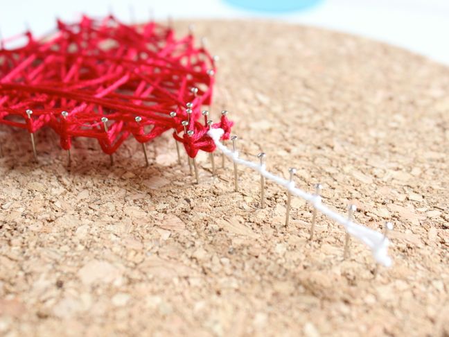 red-and-white-string-wrapped-around-pins-on-cork-diy-string-art