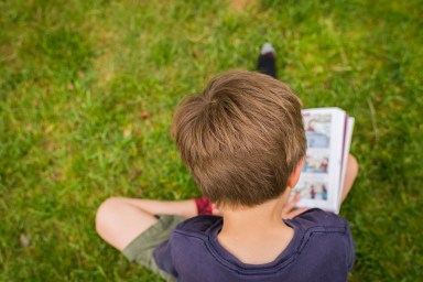 children reading a graphic novel in the grass