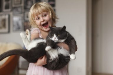 young blonde girl holding cat how to teach children to be gentle with cats