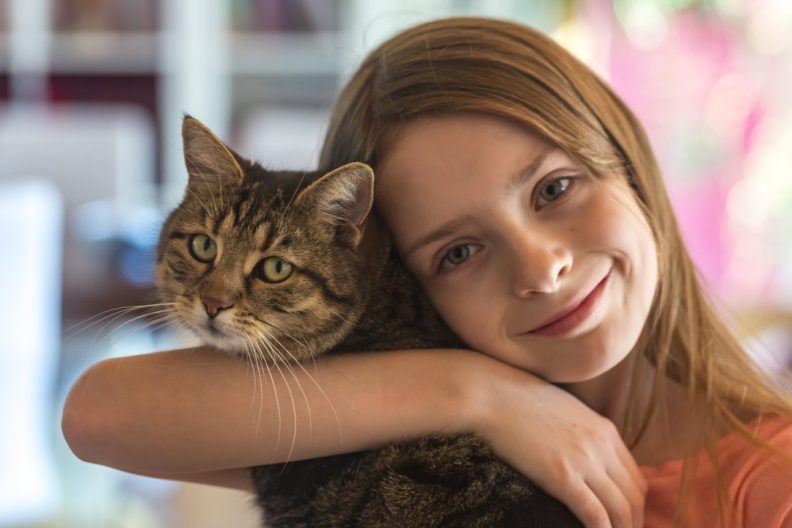 young girl hugs cat benefits of cat ownership for kids