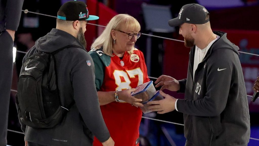 Mother Donna Kelce (C) gives cookies to her son's Jason Kelce (L) #62 of the Philadelphia Eagles and Travis Kelce (R) #87 of the Kansas City Chiefs during Super Bowl LVII Opening Night presented by Fast Twitch at Footprint Center on February 06, 2023 in Phoenix, Arizona.