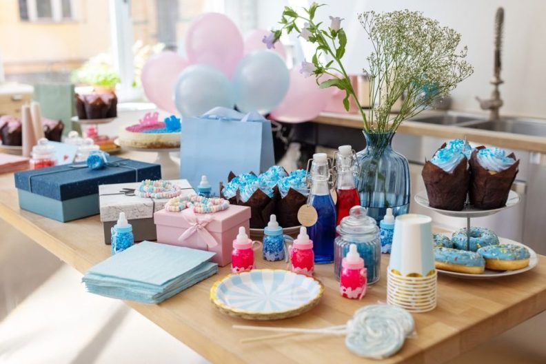 Baby shower party table with sweets. Food and drinks with gifts on decorated table at gender reveal party.