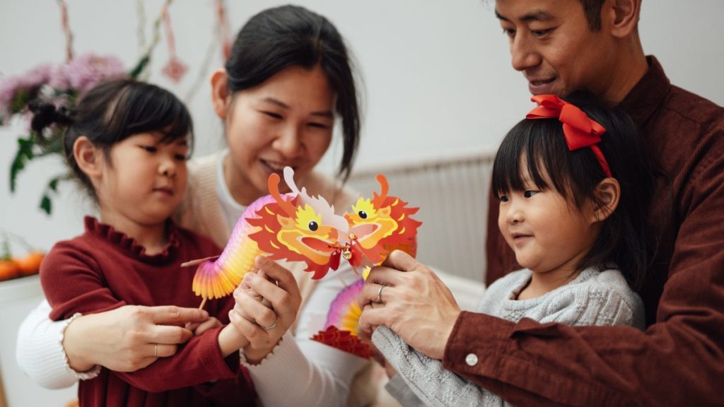 Cute Asian children playing with paper dragon while celebration Chinese New Year with family.